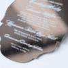 A silver mirror acrylic wedding invitation with a classic, ornate scalloped silhouette is shown at an angle against a white background. The highly reflective surface creates a liquid-like sheen, making the white printed text pop.
