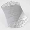 A luxurious silver mirror acrylic wedding invitation with a distinctive curved, shield-like silhouette. The top and bottom edges feature intricate laser-cut scrollwork that creates a decorative, open-work lace effect.
