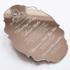 A silver mirror acrylic wedding invitation with a classic, ornate scalloped silhouette is shown at an angle against a white background. The highly reflective surface creates a liquid-like sheen, making the white printed text pop.