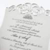 A luxurious silver mirror acrylic wedding invitation with a distinctive curved, shield-like silhouette. The top and bottom edges feature intricate laser-cut scrollwork that creates a decorative, open-work lace effect.
