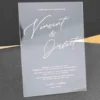 Modern clear acrylic invitation featuring elegant white script text, part of a minimalist wedding invitation suite with mailing envelopes.