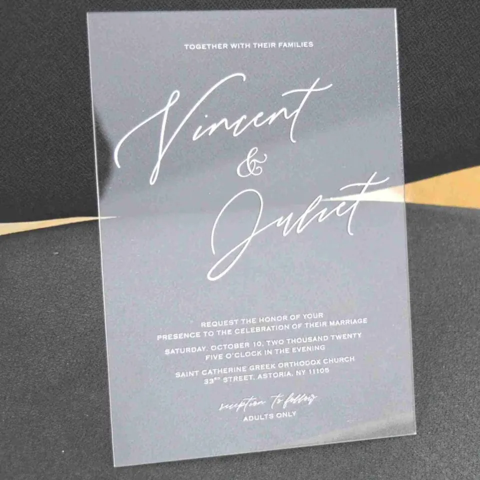 Modern clear acrylic invitation featuring elegant white script text, part of a minimalist wedding invitation suite with mailing envelopes.