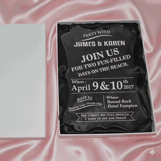 An angled, close-up view of an open white wedding invitation box resting on a soft, blush-toned fabric. The box features: A thick, clear acrylic invitation plaque** with a decorative scalloped edge, nestled inside on a black satin lining. Bold white typography on the acrylic card that reads "JOIN US FOR TWO FUN-FILLED DAYS ON THE BEACH" for a celebration on Location details for the "Round Rock Hotel Pompton" and RSVP information are clearly displayed at the bottom. The white lid of the box is partially visible, leaning against the base to reveal the luxury contents inside. The high-contrast design between the clear acrylic, white text, and dark lining creates a modern and high-end aesthetic.
