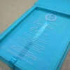 A high-angle view of an open turquoise silk invitation box resting on a textured, neutral-toned fabric surface.The presentation includes:The left panel: Features a large, ornate silver Logo encrusted with sparkling crystals.The center A clear acrylic invitation card sits within the folio, featuring the name in a delicate white script, along with formal wedding details.The right panel: Contains a pocket holding coordinating stationery, including a white RSVP, card with a silver-foiled decorative border. The overall design is vibrant and modern, accented by the shimmering silver elements.
