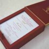 An open, **luxurious maroon wedding invitation box** featuring a multi-functional design with a built-in sweets compartment. The interior includes: * **The Invitation:** A white card printed with elegant red and gold typography for the wedding of "Rahul with Priyanka," featuring traditional Hindu motifs and "Shree Ganeshay Namah" script. * **Sweets Compartment:** To the right of the invitation, a **gold-foiled grid** provides individual sections for chocolates or traditional sweets. * **Inner Lid:** The maroon lid is accented with a thin gold border and a central gold-foiled religious inscription. * The box has a deep, textured wood-grain or fabric finish, giving it a high-end and traditional look. * The entire piece is set against a neutral, light-colored background, emphasizing the rich color palette of maroon and gold.