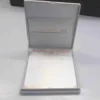An open, **luxurious white wedding invitation box** featuring a formal stationery suite with gold accents. The interior includes: * A **white invitation card** in the base, printed with elegant **gold foil calligraphy** and framed by intricate gold scrollwork flourishes at the top and bottom. * The **inner lid** features a horizontal pocket holding a matching white card, also featuring a gold script heading. * The box is lined with a smooth, white fabric that gives it a clean and high-end appearance. * The top edge of the lid shows a hint of the **gold pearl-encrusted exterior**. * Set against a neutral, light grey background, the focus remains on the bright white textures and reflective gold detailing of the suite.