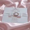 Ivory silk save the date card, adorned with a stunning rhinestone brooch on satin ribbon and printed with gold foil.