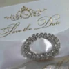 Ivory silk save the date card, adorned with a stunning rhinestone brooch on satin ribbon and printed with gold foil.