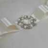 Ivory silk wedding invitation box with a luxury pearl brooch, satin ribbon, and handmade artisan padding.