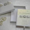 Handmade silk wedding invitation box adorned with a crystal rhinestone and pearl brooch for luxury wedding stationery.