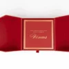 An overhead view of the open, deep red invitation box from the previous image. The two side flaps are spread wide, showing their angled, geometric construction. Inside the central compartment, a matching red card is framed by a double gold border. The card features the word "Venus" in elegant gold script, with a smaller line of gold text above it that reads, "Because there's no diamond too big or party too grand for." A small red ribbon pull-tab is visible at the bottom center of the box.
