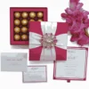 A flat-lay arrangement of a magenta-colored wedding stationery and chocolate gift set. The set includes a square magenta silk box lid decorated with crossing light pink satin ribbons and a large, ornate pink crystal brooch. To the left, the open base of the box reveals a 16-compartment tray filled with gold-wrapped chocolate truffles. Below the box are several stationery items: a formal white invitation card with magenta borders, a matching RSVP card, and a white envelope addressed to "Mathew and Michelle." A stem of bright pink gladiolus flowers lies along the right side against a clean white background.
