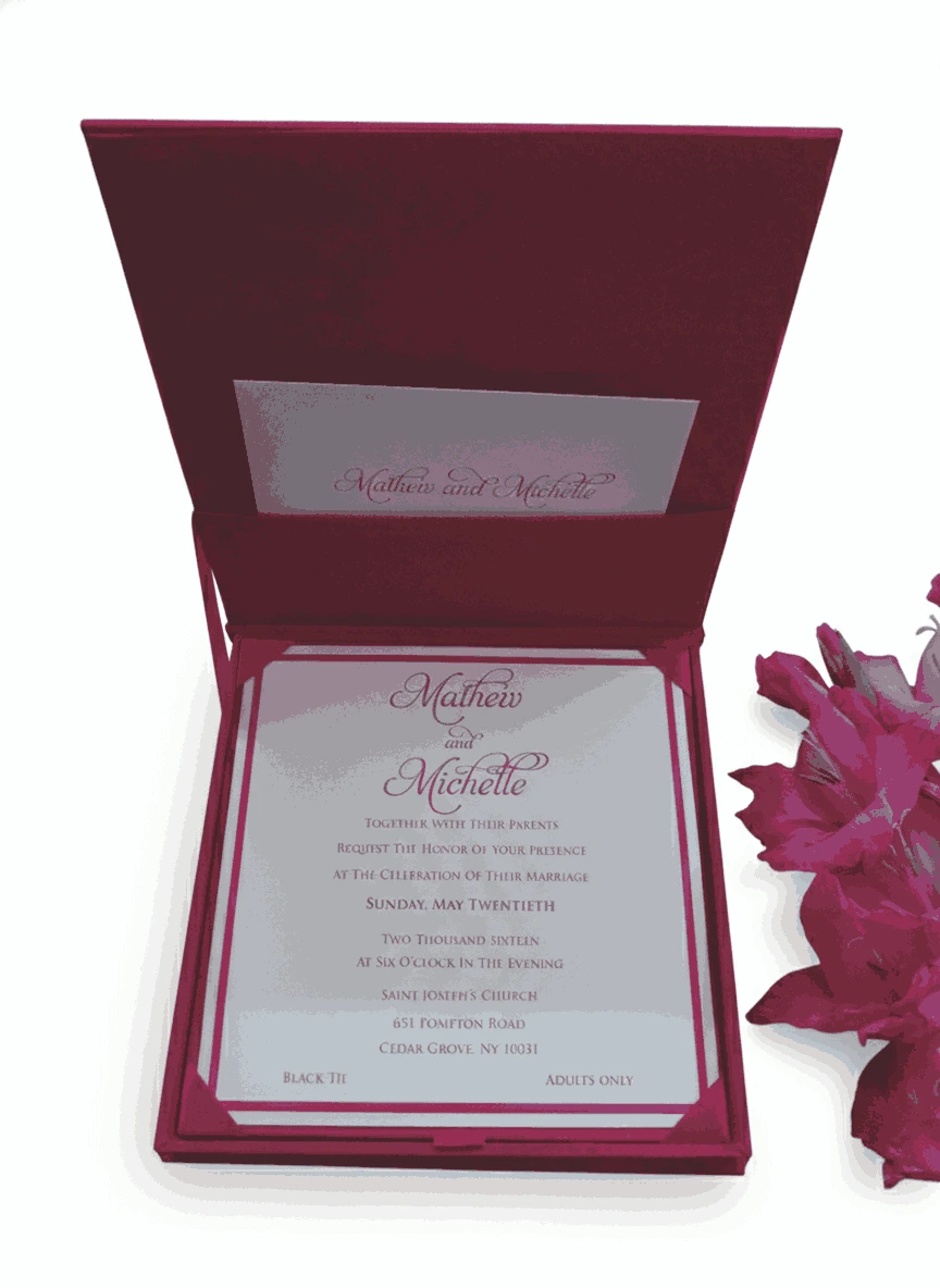 An open, square magenta silk invitation box displayed alongside its contents. The interior of the lid features a vertical magenta band on the left with a gold laser-cut floral pattern and a white panel on the right with elegant pink script. The main base of the box holds a matching white invitation card with magenta borders. A stem of vibrant pink gladiolus flowers lies to the right, and the entire set is presented on a clean white background.c