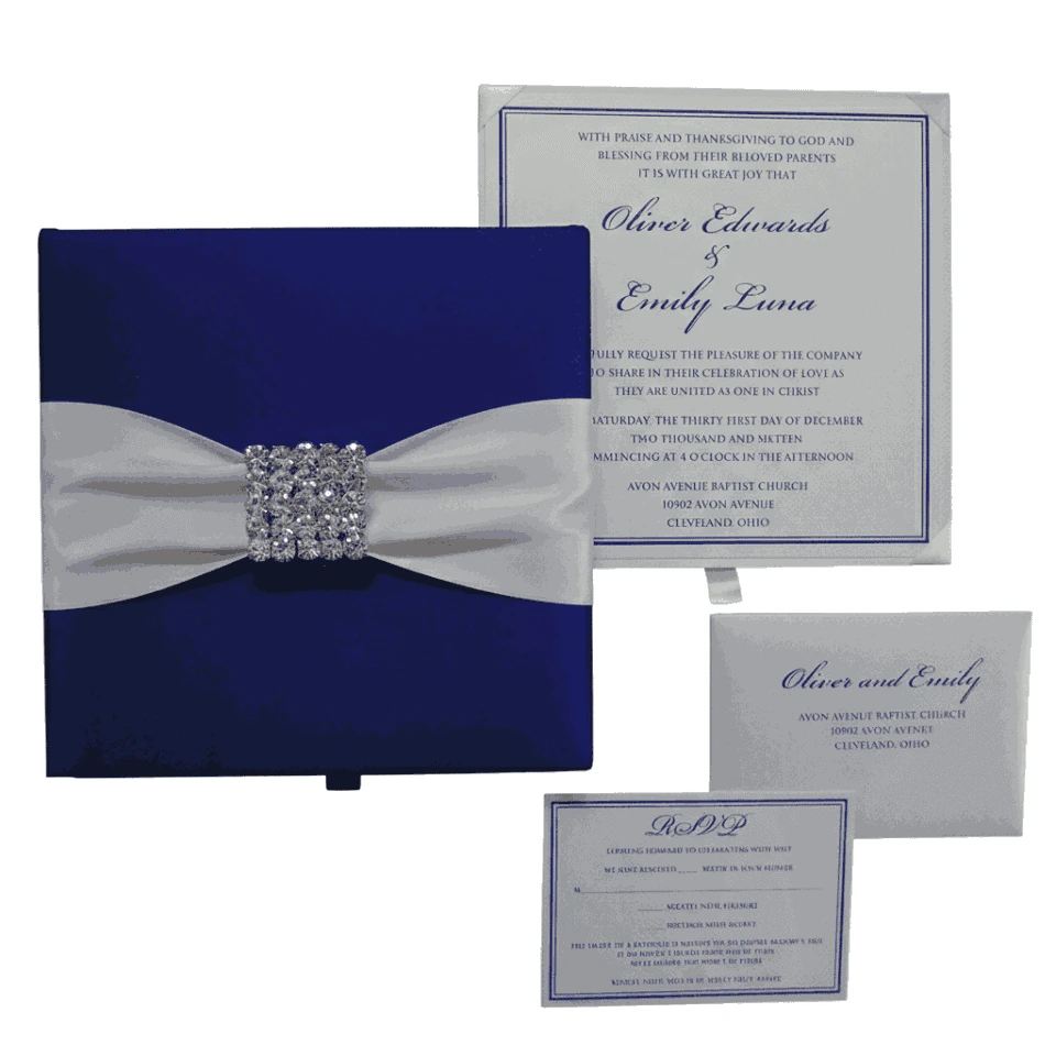 A top-down arrangement of a navy blue wedding stationery set. It includes a closed silk box featuring a wide white satin ribbon and a square crystal buckle. Beside the box is a formal white wedding invitation for Oliver Edwards and Emily Luna, a matching RSVP card, and a white envelope.