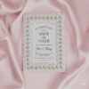 An ivory silk save the date card embroidered with faux pearls and rhinestones, with details printed with black foil on a pearl shimmery cardstock.
