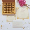 A gold-themed wedding invitation card set including an open box base filled with sixteen gold-wrapped chocolate truffles in a grid. A formal invitation for "Mathew and Michelle," an RSVP card, and an envelope are arranged alongside vibrant pink gladiolus flowers on a white surface with scattered petals.