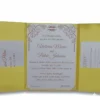 A rectangular, olive-green silk wedding invitation folio oriented vertically. The design features a gate-fold opening with two panels meeting in the center. A shimmering taupe or champagne-colored satin ribbon wraps horizontally around the folio, cinched at the middle by a large, sparkling silver rhinestone brooch with a geometric, butterfly-inspired silhouette. The folio is set against a plain white background, casting a soft shadow at the base.
