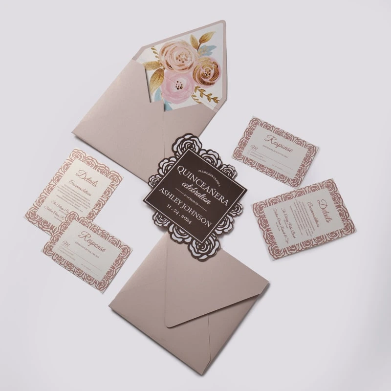An elegant Quinceañera invitation suite featuring a dusty rose and rose gold color palette, laid out on a light gray background. The set includes several coordinated pieces: Main Invitation: A square, chocolate-brown card with a decorative rose gold laser-cut floral border made of rose patterns. The white and rose gold text reads, "PLEASE JOIN US FOR A QUINCEAÑERA celebration IN HONOR OF ASHLEY JOHNSON" with the date "11.24.2024." Enclosure Cards: Three white cards featuring a matching rose gold floral pattern around the edges. These include two "Response" (RSVP) cards and one "Details" card for accommodations. Envelope: A dusty rose envelope is shown open, revealing a luxurious floral liner featuring large painted roses in shades of cream, pink, and gold with gold leaf accents. A second invitation card is partially tucked inside.