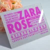 A square silver glitter Bat Mitzvah invitation with peach and pink roses.The invitation features a mix of textures and bold purple typography.