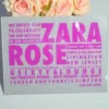 A square silver glitter Bat Mitzvah invitation with peach and pink roses.The invitation features a mix of textures and bold purple typography.