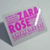 A square silver glitter Bat Mitzvah invitation with peach and pink roses.The invitation features a mix of textures and bold purple typography.