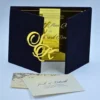 An opulent wedding invitation set featuring a **black velvet gatefold folio**. Inside, the invitation is printed on a highly reflective **gold mirror acrylic** surface. The folio is held closed by a large, custom-cut **gold mirror acrylic monogram** featuring the initials. In the foreground, a textured cream envelope addressed to in navy blue script sits atop a matching RSVP or detail card with ornate navy flourishes. The entire suite is set against a clean, white background.