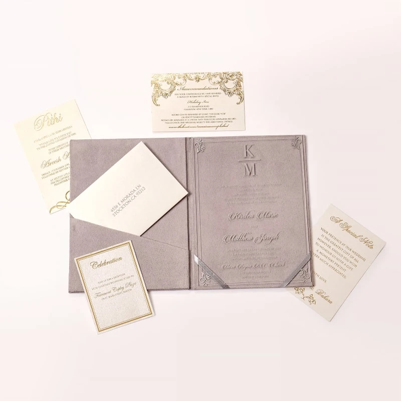 An open, mauve-colored velvet folio and Acrylic wedding invitation set displayed on a white background. The folio features a pocket on the left side holding a cream-colored envelope with a printed address, and a "Celebration" card with a silver border resting in front.