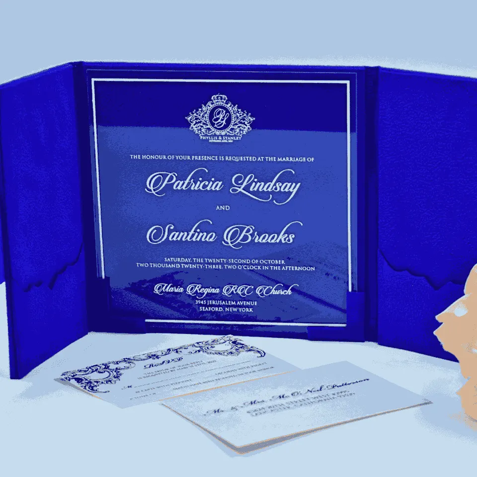 An open royal blue velvet tri-fold wedding invitation shown from a slightly elevated angle. The central panel holds a clear acrylic invitation card with crisp white text, featuring the names in an elegant script.