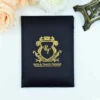 A top-down view of a sophisticated black silk wedding invitation folder on a white surface. The cover features a striking gold-foil crest in the center, topped with a crown and containing the monogrammed initials Below the crest, the names are printed in bold, gold-foil capital letters.