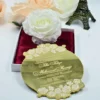 This image showcases a luxurious gold mirror acrylic wedding invitation with a unique, scalloped circular shape. It is positioned in front of an open white box lined with rich burgundy satin, which holds a large, white Box.