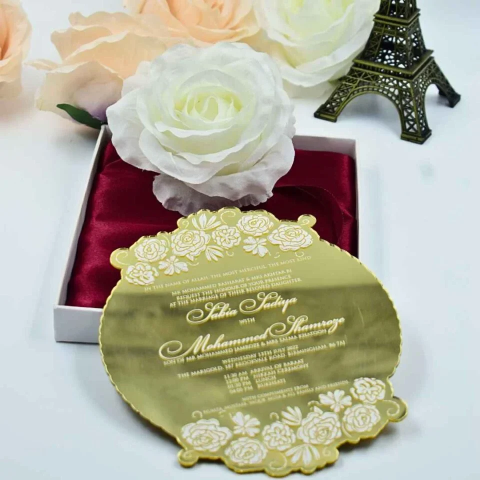 This image showcases a luxurious gold mirror acrylic wedding invitation with a unique, scalloped circular shape. It is positioned in front of an open white box lined with rich burgundy satin, which holds a large, white Box.