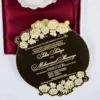 This image showcases a luxurious gold mirror acrylic wedding invitation with a unique, scalloped circular shape. It is positioned in front of an open white box lined with rich burgundy satin, which holds a large, white Box.