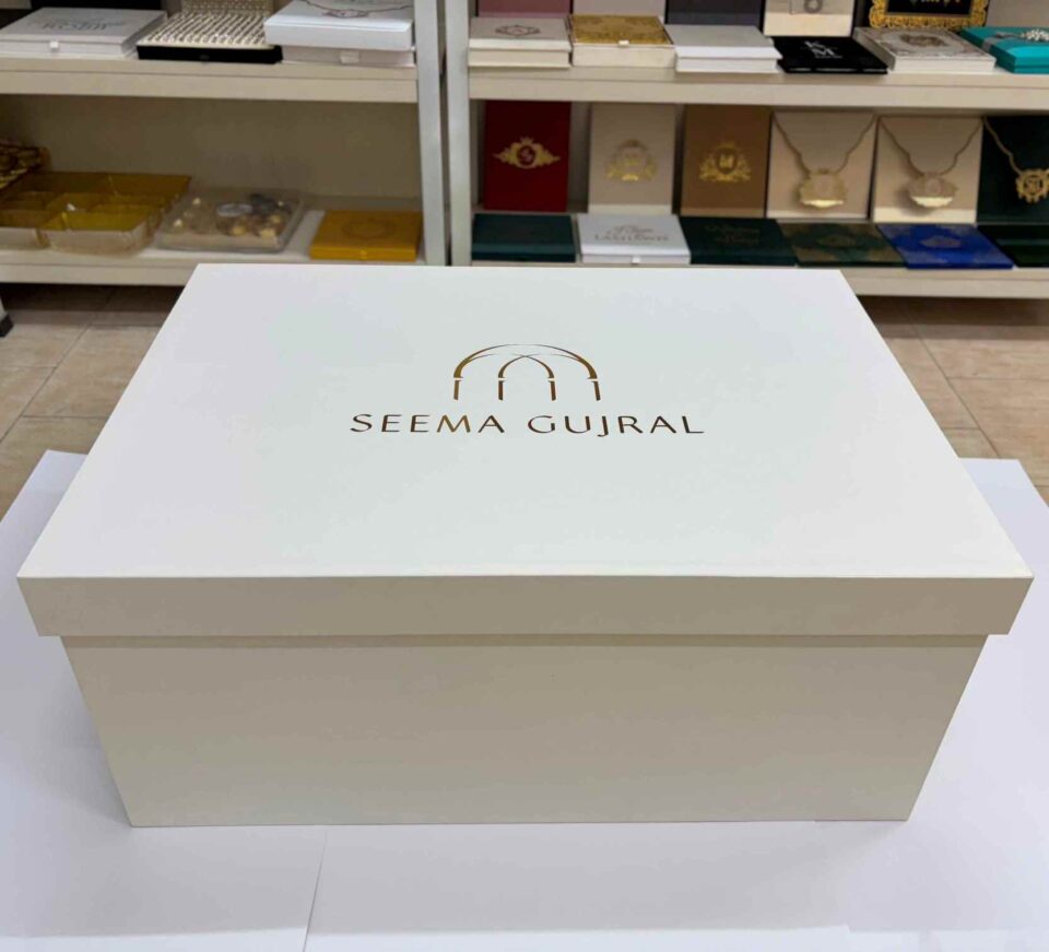 Luxury bridal lehenga box crafted from 7mm MDF featuring a white pearl shimmer finish, custom gold foil branding for a fashion designer, and premium side handles for couture trousseau packaging.