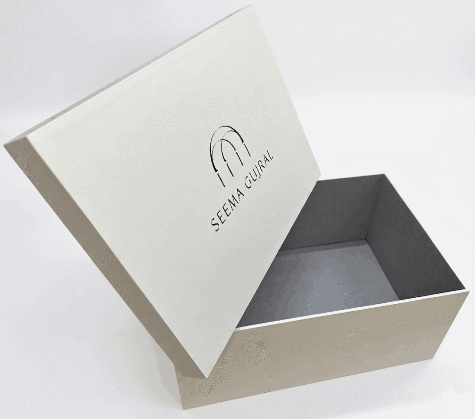 Luxury bridal lehenga box crafted from 7mm MDF featuring a white pearl shimmer finish, custom gold foil branding for a fashion designer, and premium side handles for couture trousseau packaging.