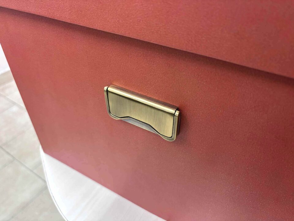 A high-end bridal lehenga trunk box made of a thick orange MDF frame with a smooth matte finish, featuring a custom gold foil-pressed logo on the lid and a sturdy antique brass handle on the side for professional fashion packaging.