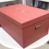 A high-end bridal lehenga trunk box made of a thick orange MDF frame with a smooth matte finish, featuring a custom gold foil-pressed logo on the lid and a sturdy antique brass handle on the side for professional fashion packaging.