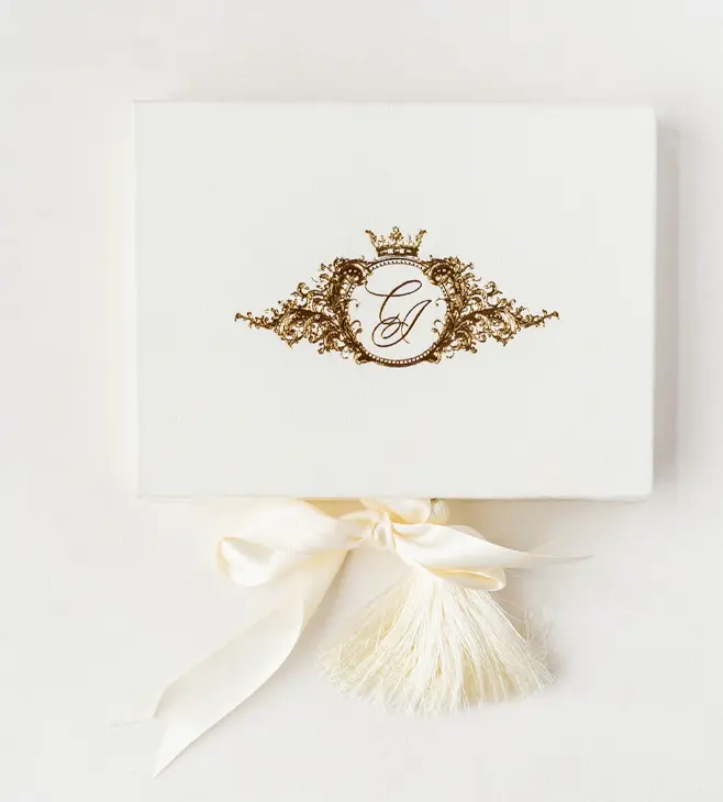 Ivory velvet wedding invitation box with a gold foil monogram