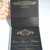 Open satin wedding invitation box showing gold foil Bible verse and acrylic invitation card inside