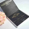Angled view of open satin invitation box with gold foil scripture lining and ornate acrylic invite