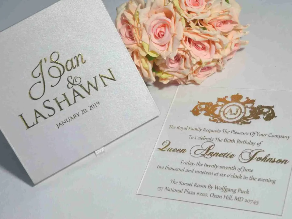 Satin invitation box lid beside its matching gold foil acrylic wedding invitation card and roses