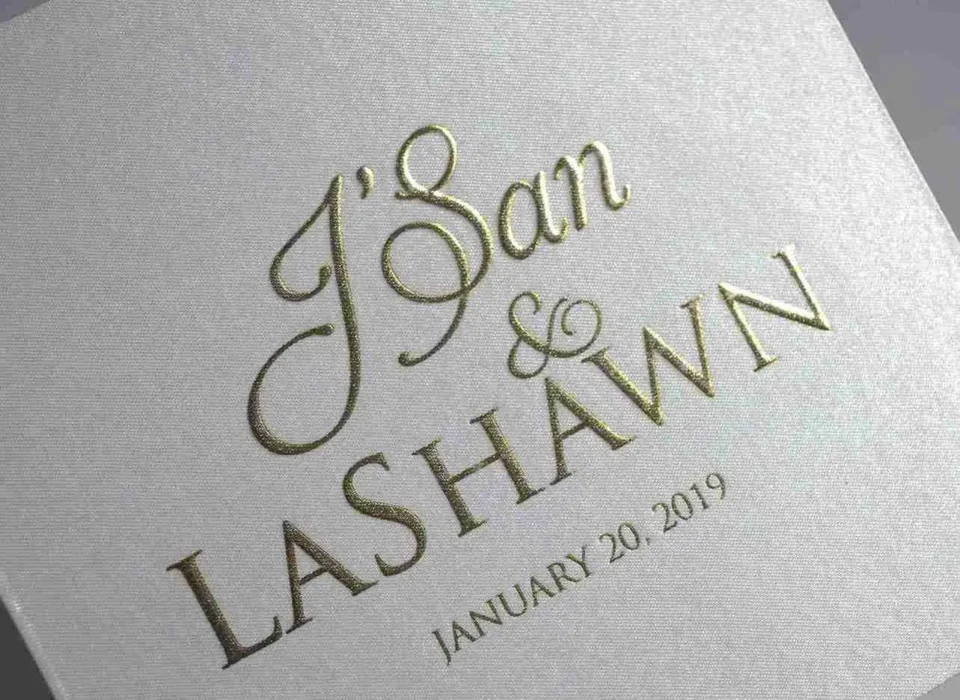 Close-up of gold foil-stamped names and wedding date on ivory satin invitation box cover